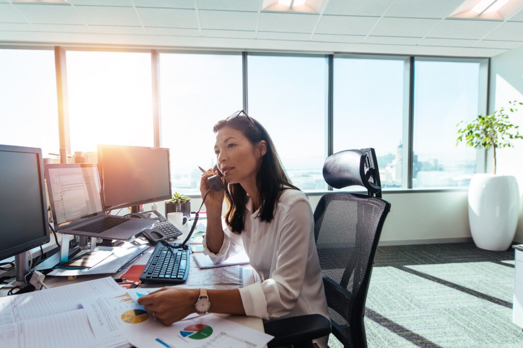 Business professional engaged in a phone call while analyzing reports at a modern office desk